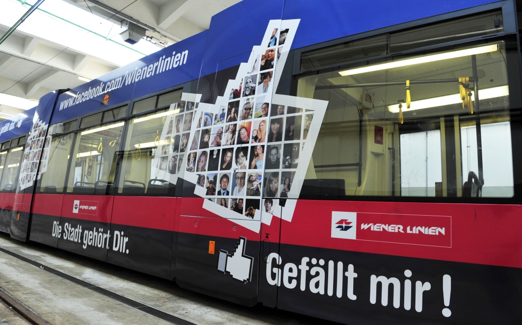 Zwei mit Fotos von Facebook-Freunden der Wiener Linien gestalteten Niederflurstraßenbahn - ULF - werden beklebt.