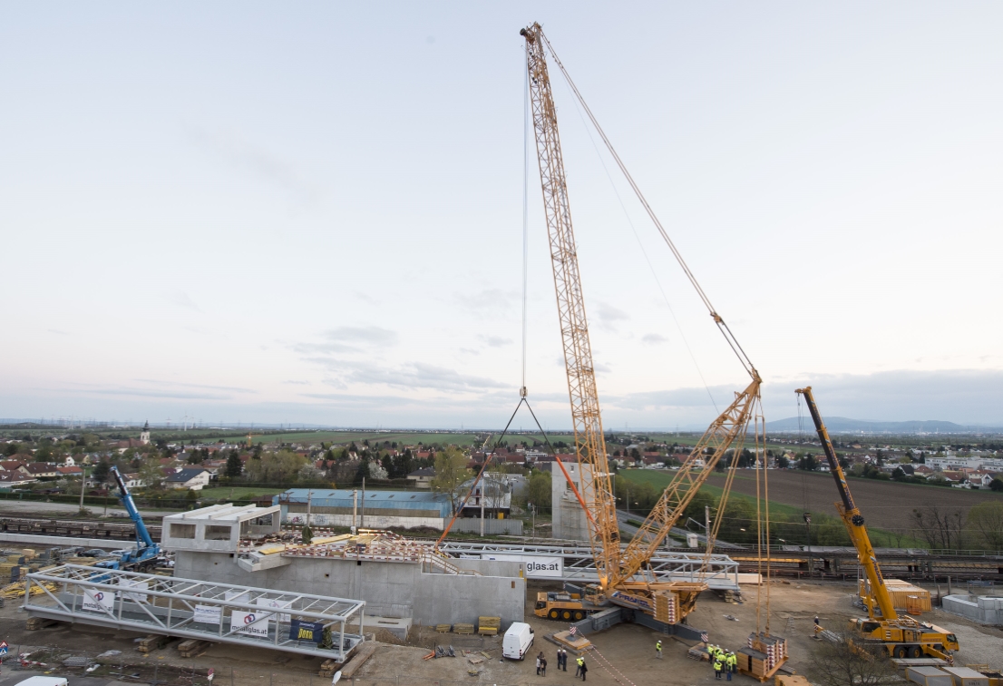 Baustelle der U1 Verlängerung in Oberlaa mit Schwerlastkran. Hebearbeiten von Fußgängersteg über die ÖBB Gleisanlage werden vorbereitet.