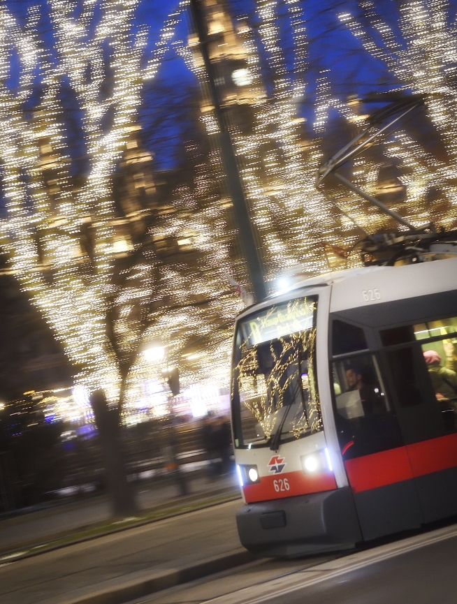 Fahrzeuge der Wiener Linien im weihnachtlich beleuchteten Wien. Hier eine Straßenbahn vor dem Rathausplatz.