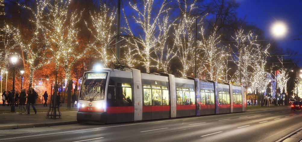 Fahrzeuge der Wiener Linien im weihnachtlich beleuchteten Wien. Hier eine Straßenbahn vor dem Rathausplatz.