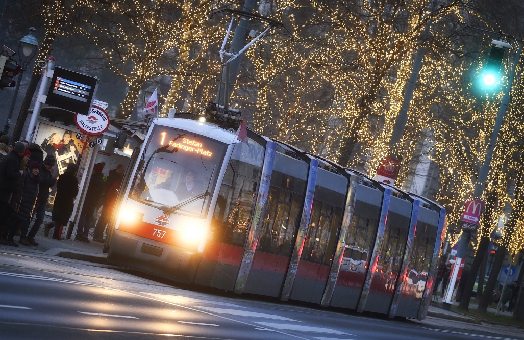 Fahrzeuge der Wiener Linien im weihnachtlich beleuchteten Wien. Hier eine Straßenbahn vor dem Rathausplatz.