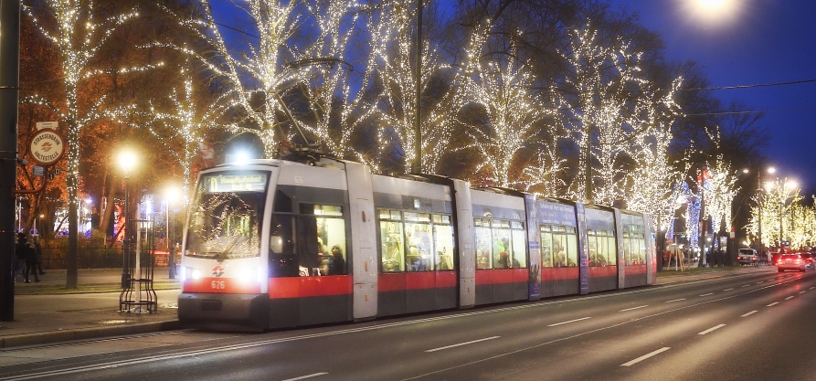 Fahrzeuge der Wiener Linien im weihnachtlich beleuchteten Wien. Hier eine Straßenbahn vor dem Rathausplatz.