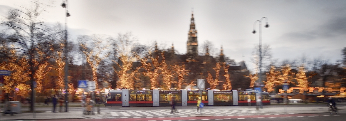 Fahrzeuge der Wiener Linien im weihnachtlich beleuchteten Wien. Hier eine Straßenbahn vor dem Rathausplatz.