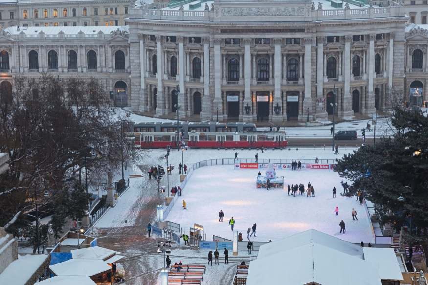 Der Wiener Eistraum am Rathausplatz mit Burgtheater im Hintergrund und Zug der Linie 1