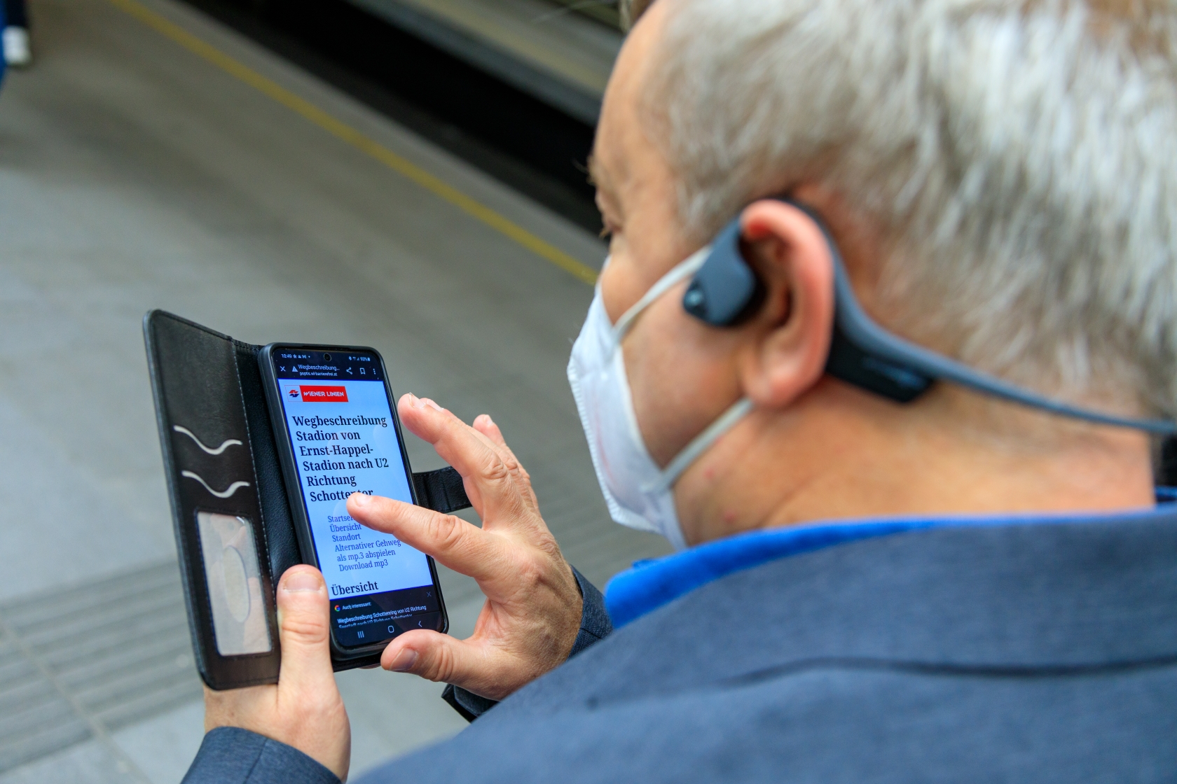 Ein blinder Fahrgast verwendet das POPTIS-Navigationssystem auf seinem Smartphone. 